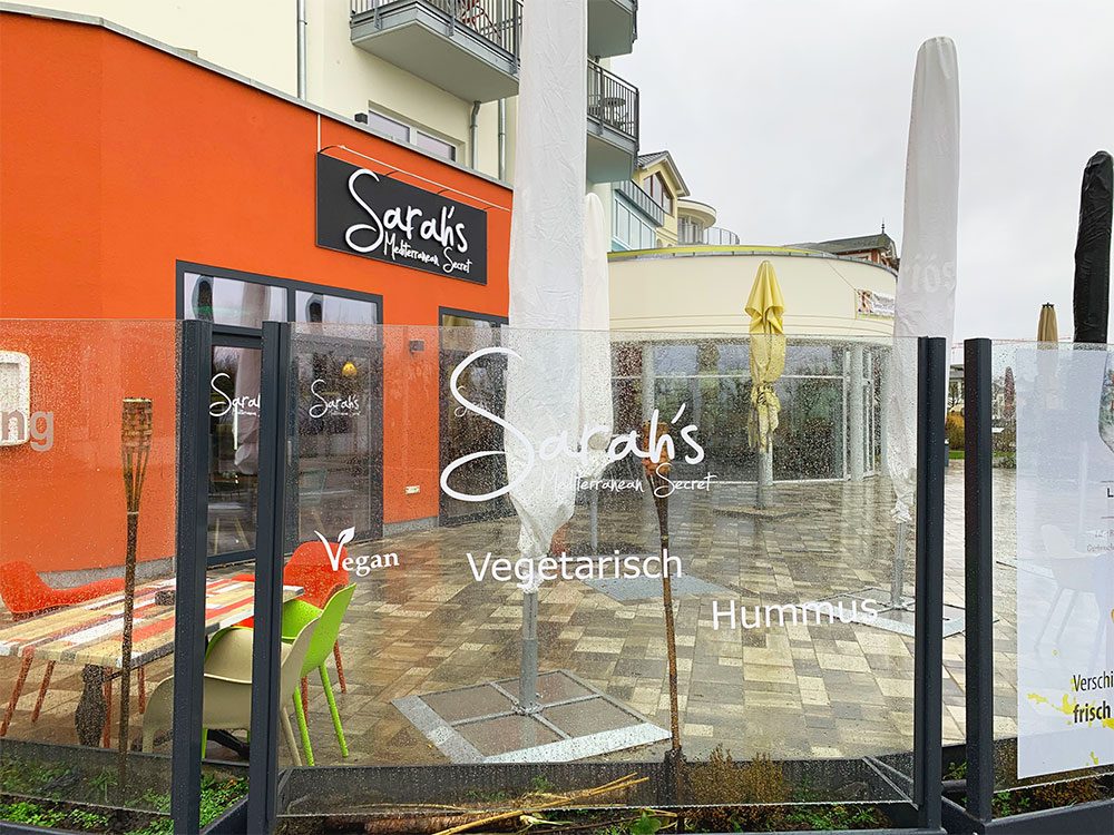 Sarah's Mediterranean Secret — Terrasse bei Tag an der Strandpromenade